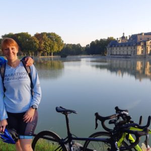 a woman standing next to a lake with bikes