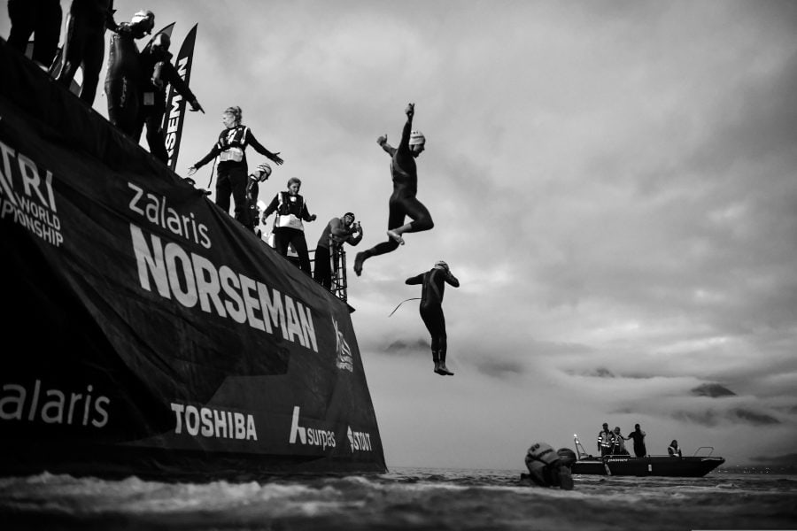 Bannières et athlètes lors d'un triathlon en bord de mer.
