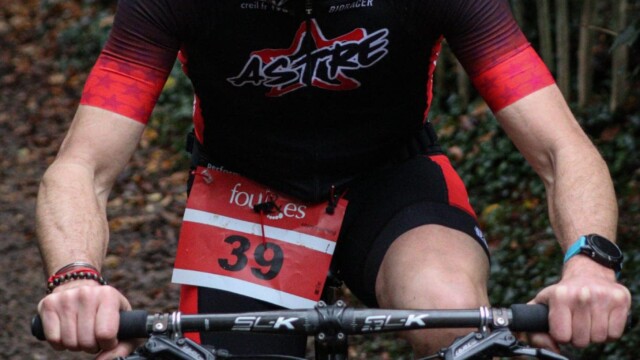 Participant en pleine action lors d'un triathlon, portant un casque et un équipement de cyclisme. Conducteur de VTT lors d'un triathlon dans la forêt.