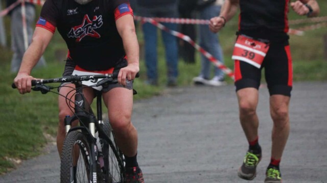 Deux triathlètes portant des maillots Astre Creillois en pleine course, cyclisme sur parcours en nature, ambiance sportive et entraînement, événement sportif local. Photos de participants lors du triathlon Astre Creillois, cyclisme, compétition, sport en plein air, passion sportives.