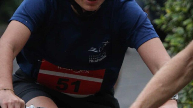 Moment intense dans un triathlon avec une participante concentrée pour la course. Vélo de triathlon d'une athlète lors d'une épreuve, portant un casque pour sécurité.